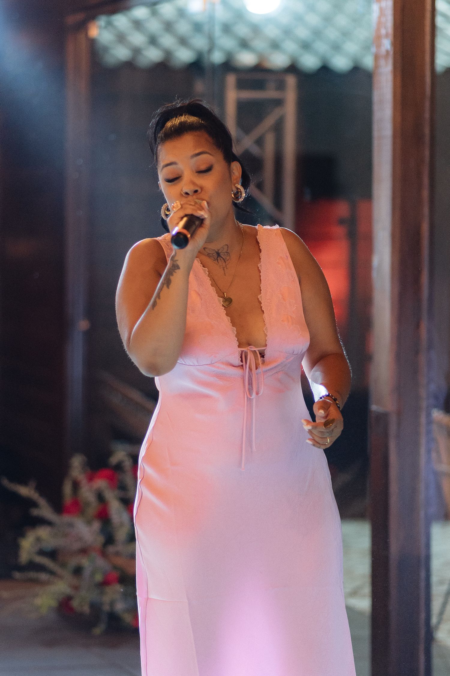Singer performing in a pink-lit venue during an evening celebration.