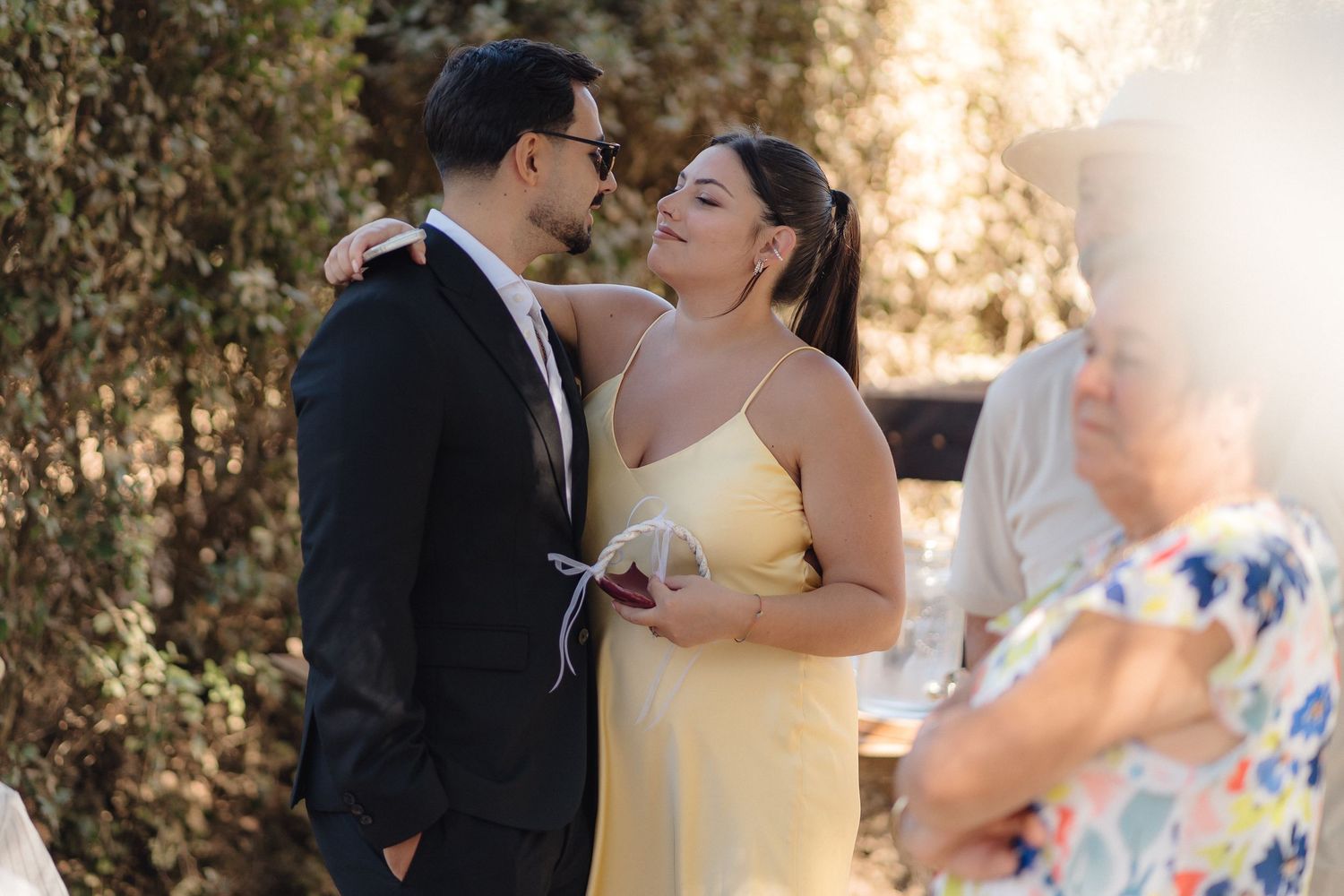 Couple sharing intimate moment at outdoor celebration in formal attire.