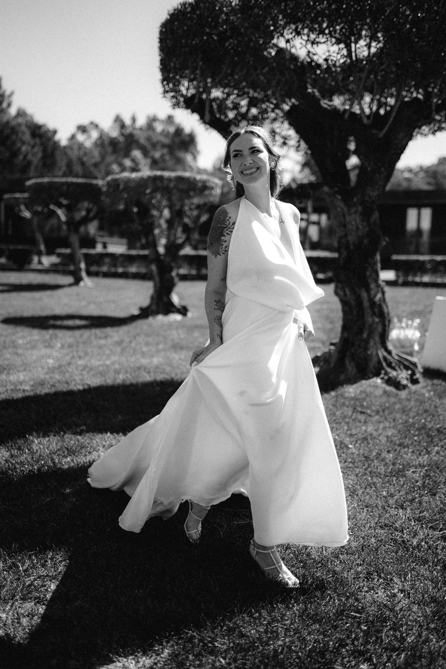 An ethereal wedding dress catches the breeze in a black and white outdoor portrait.