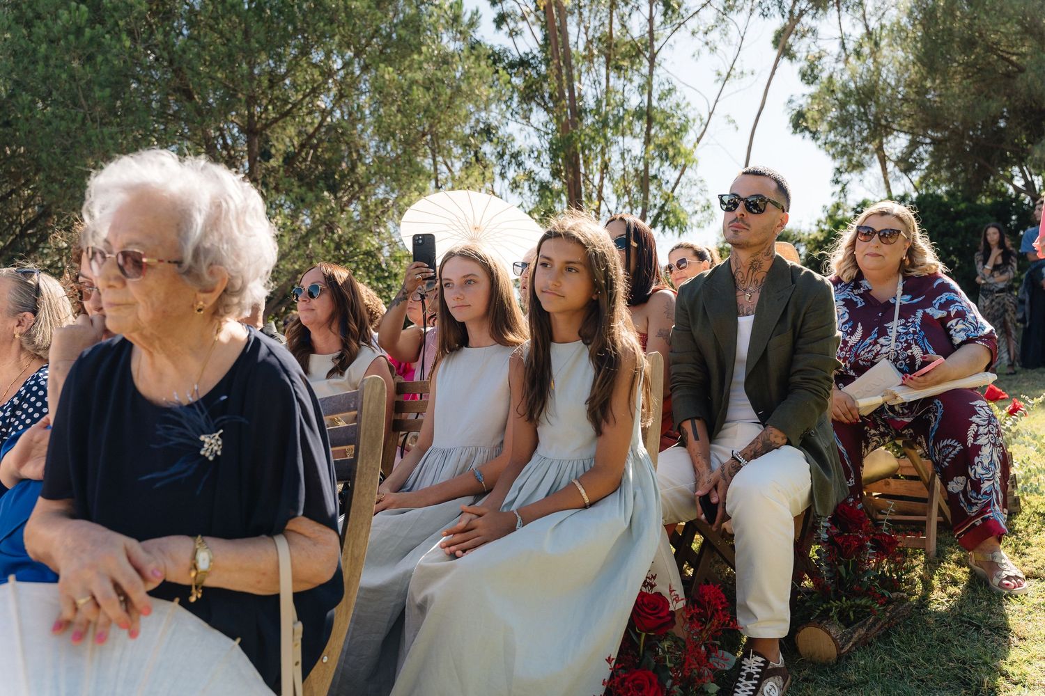 Wedding guests seated outdoors watching ceremony with eucalyptus trees in background.