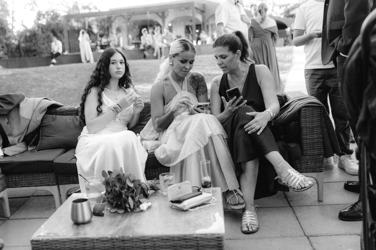 Wedding guests relaxing and socializing on outdoor benches.