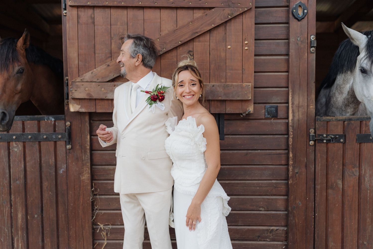 A couple shares a joyful moment in front of rustic wooden barn doors.
