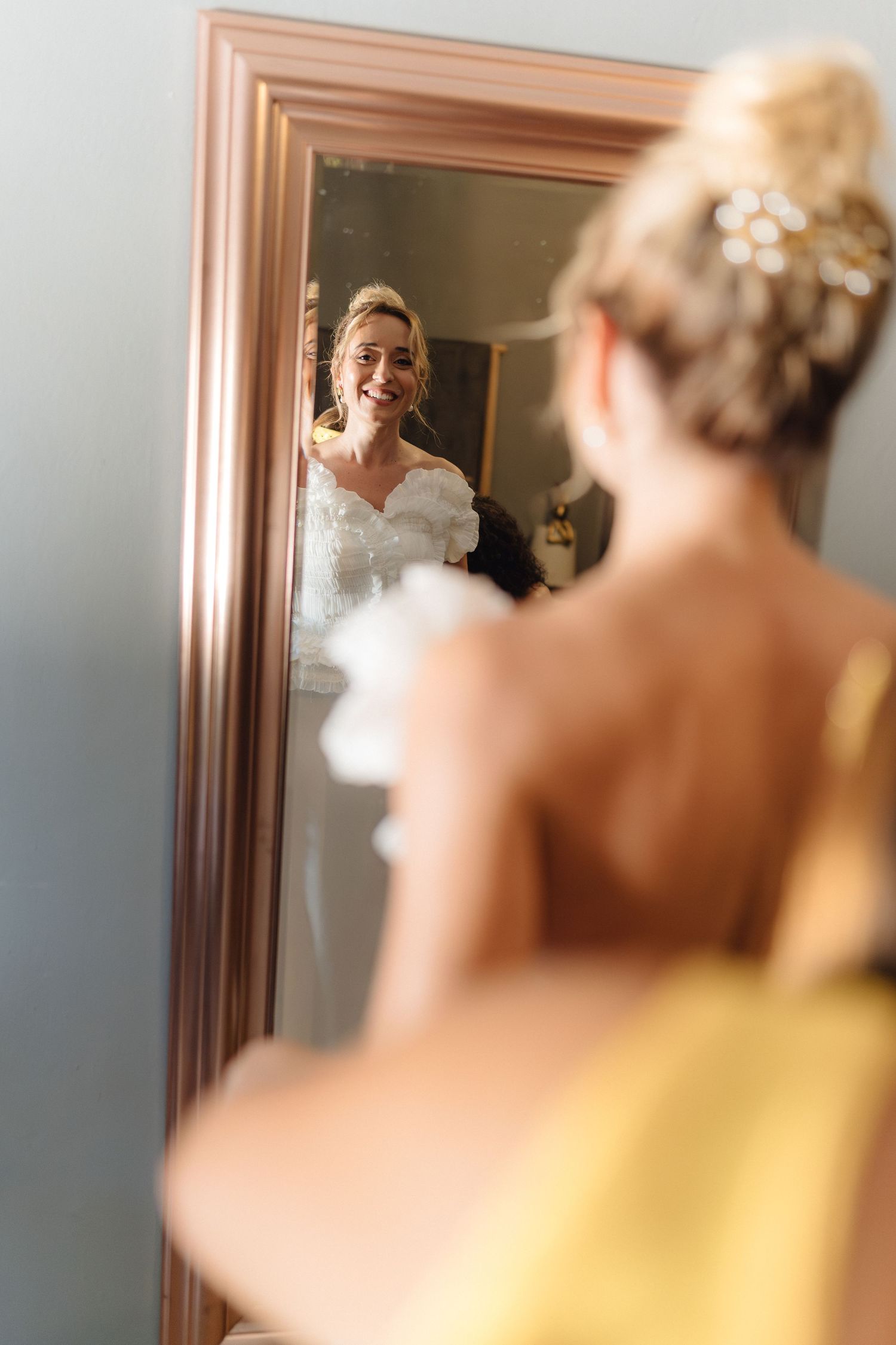 Close-up reflection of a bride's elegant updo hairstyle with delicate floral hairpiece in a mirror.
