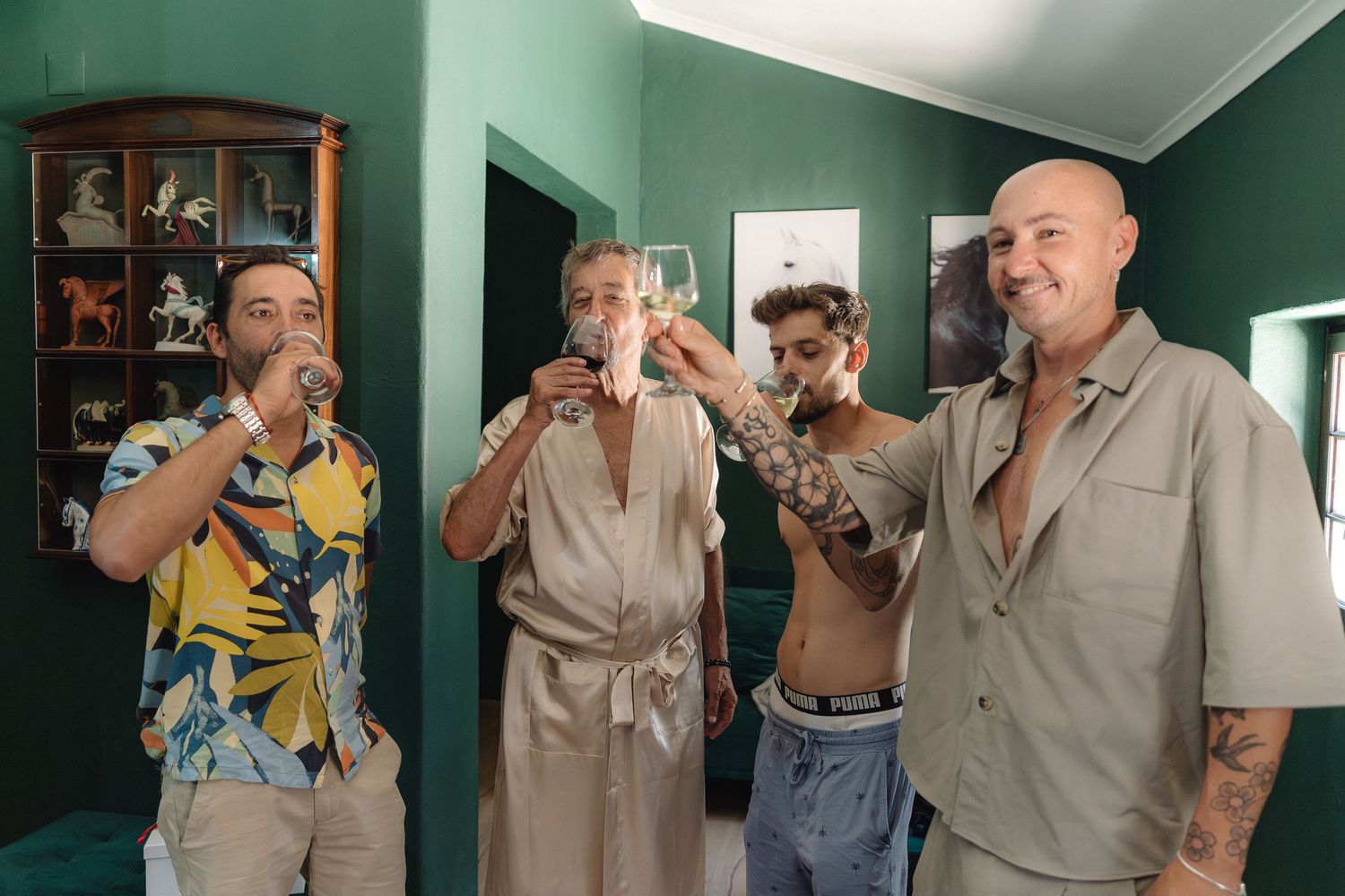 Group enjoying drinks together in a room with green walls and wooden display cabinet.