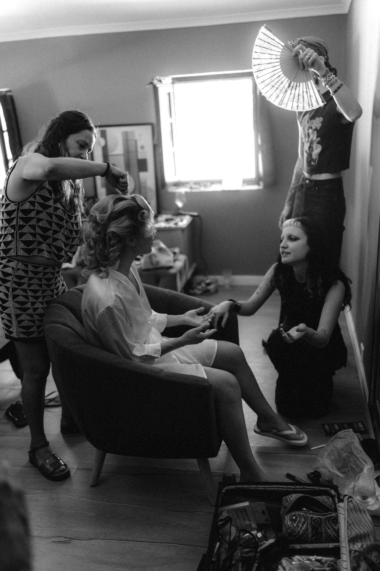 Wedding preparation scene in black and white with decorative fans and styling.