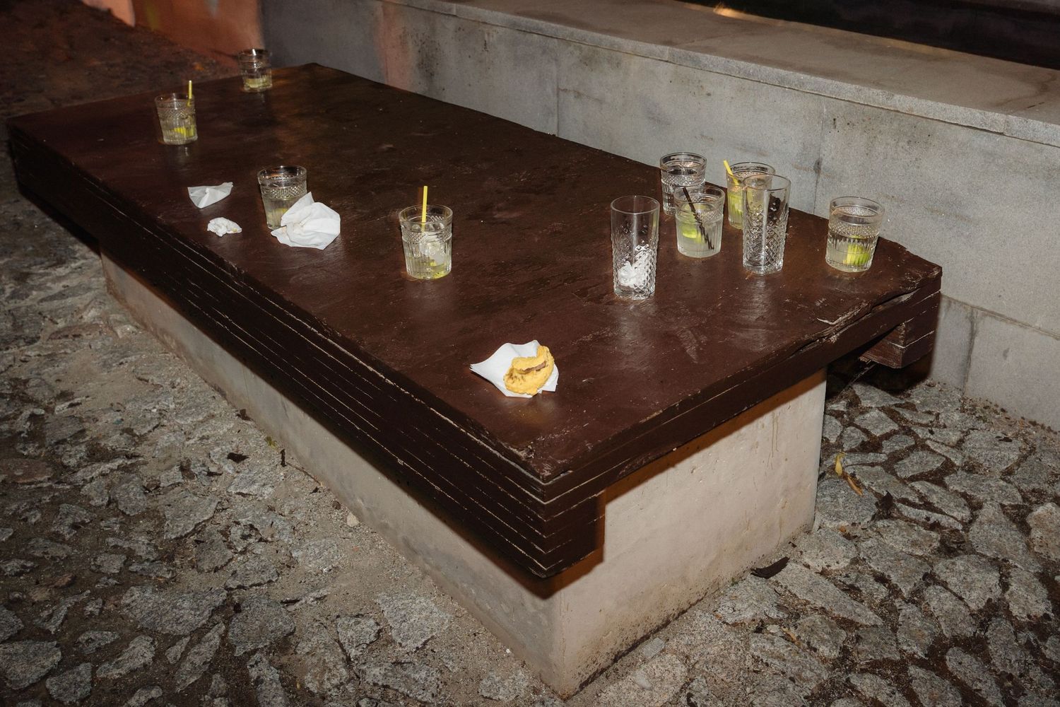 Empty drinks and glasses left on a dark wooden table at a reception.