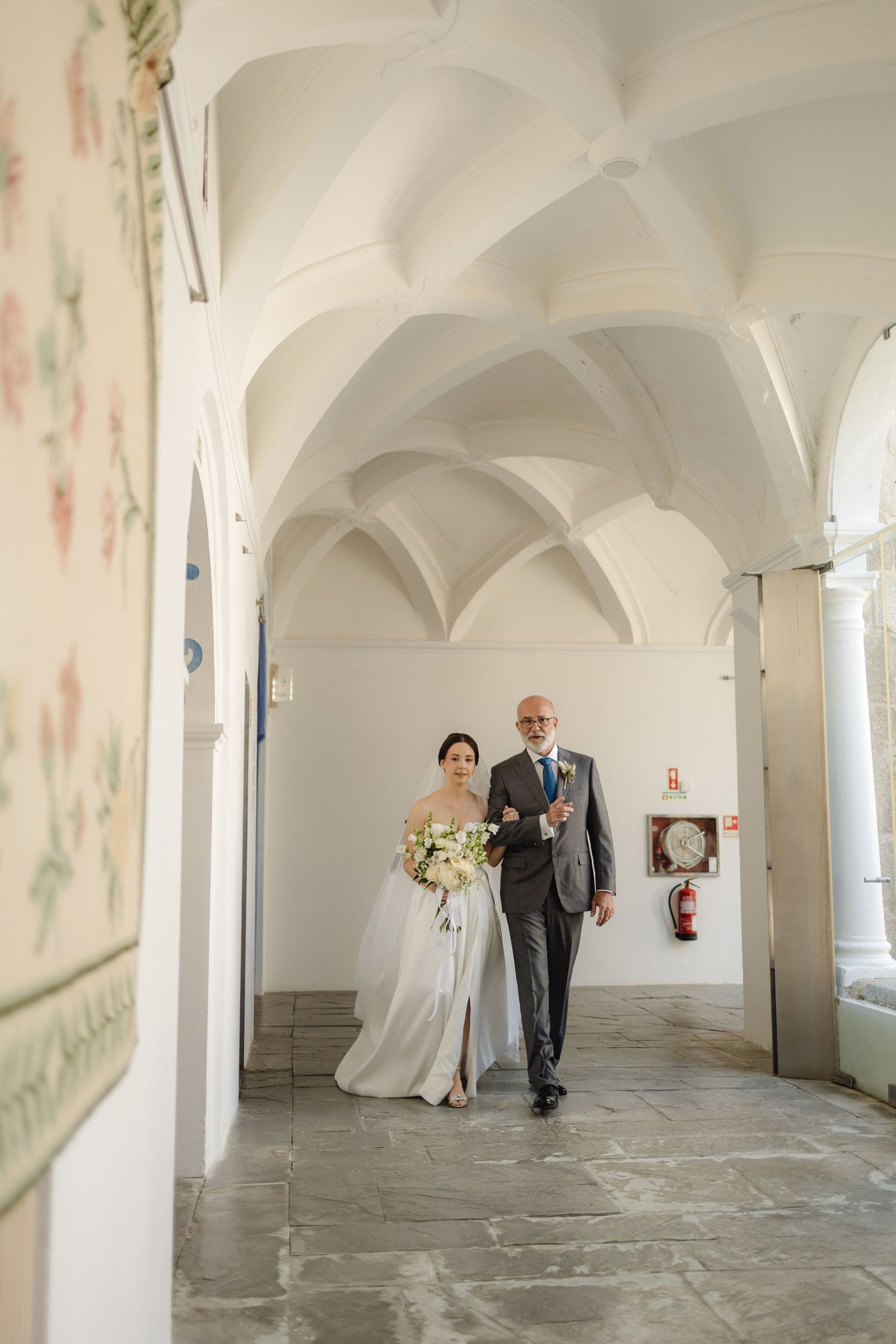 White arched hallway with vaulted ceilings and stone floors.