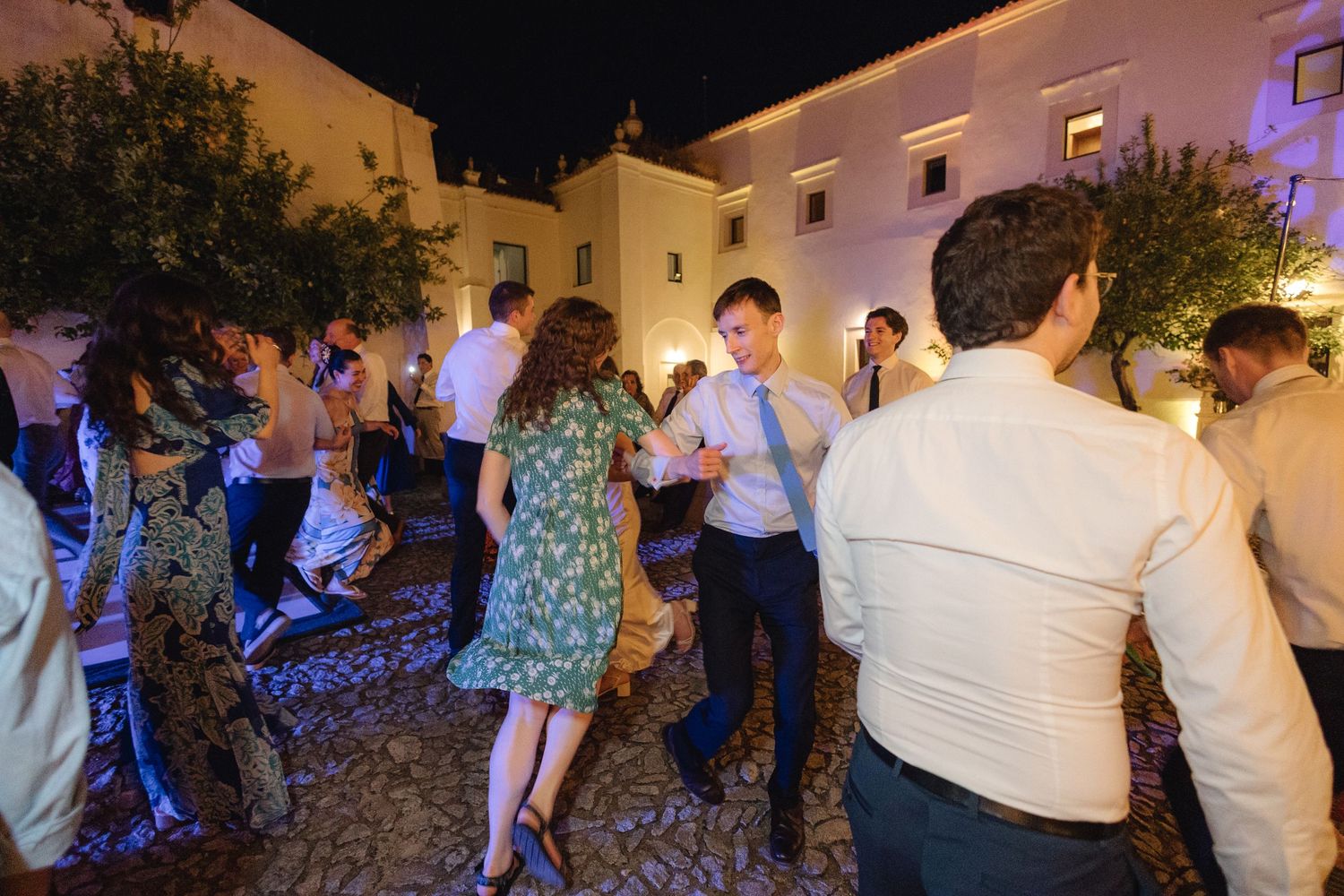 Evening wedding reception with guests dancing outdoors under string lights.