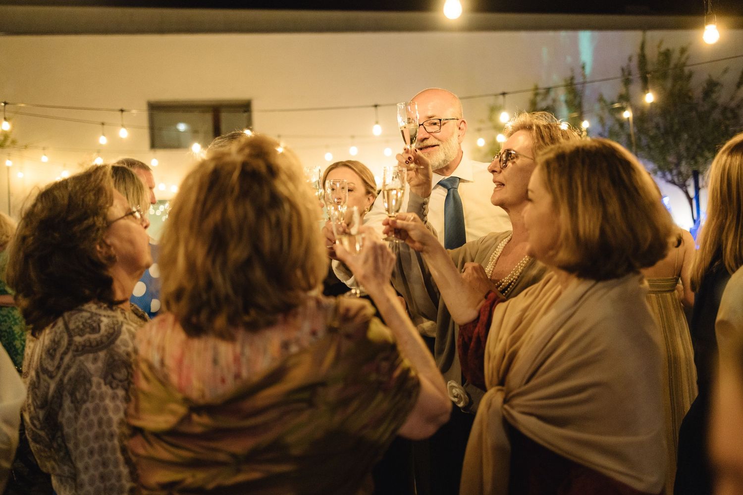 Wedding reception guests mingling under warm evening lighting.