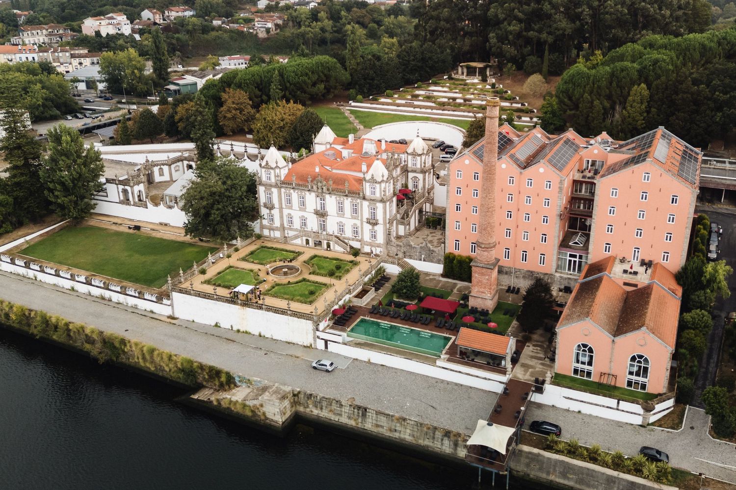 Aerial panoramic view of coastal mansions and estates along a waterfront with manicured gardens and docks.
