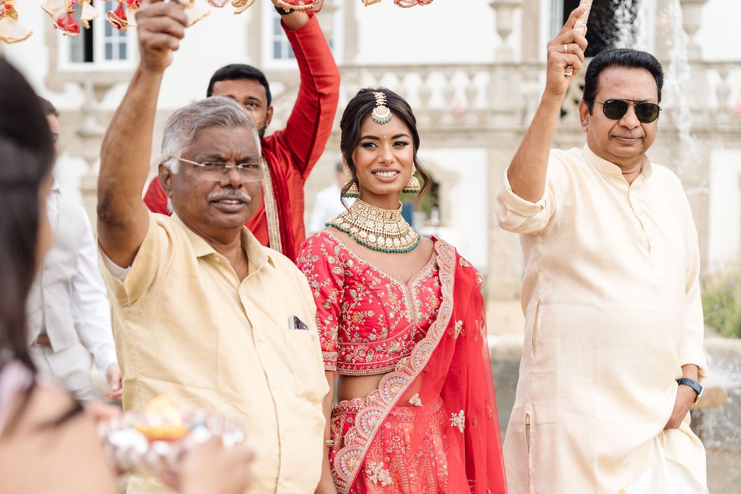Joyful wedding celebration with guests in traditional Indian attire waving and celebrating.