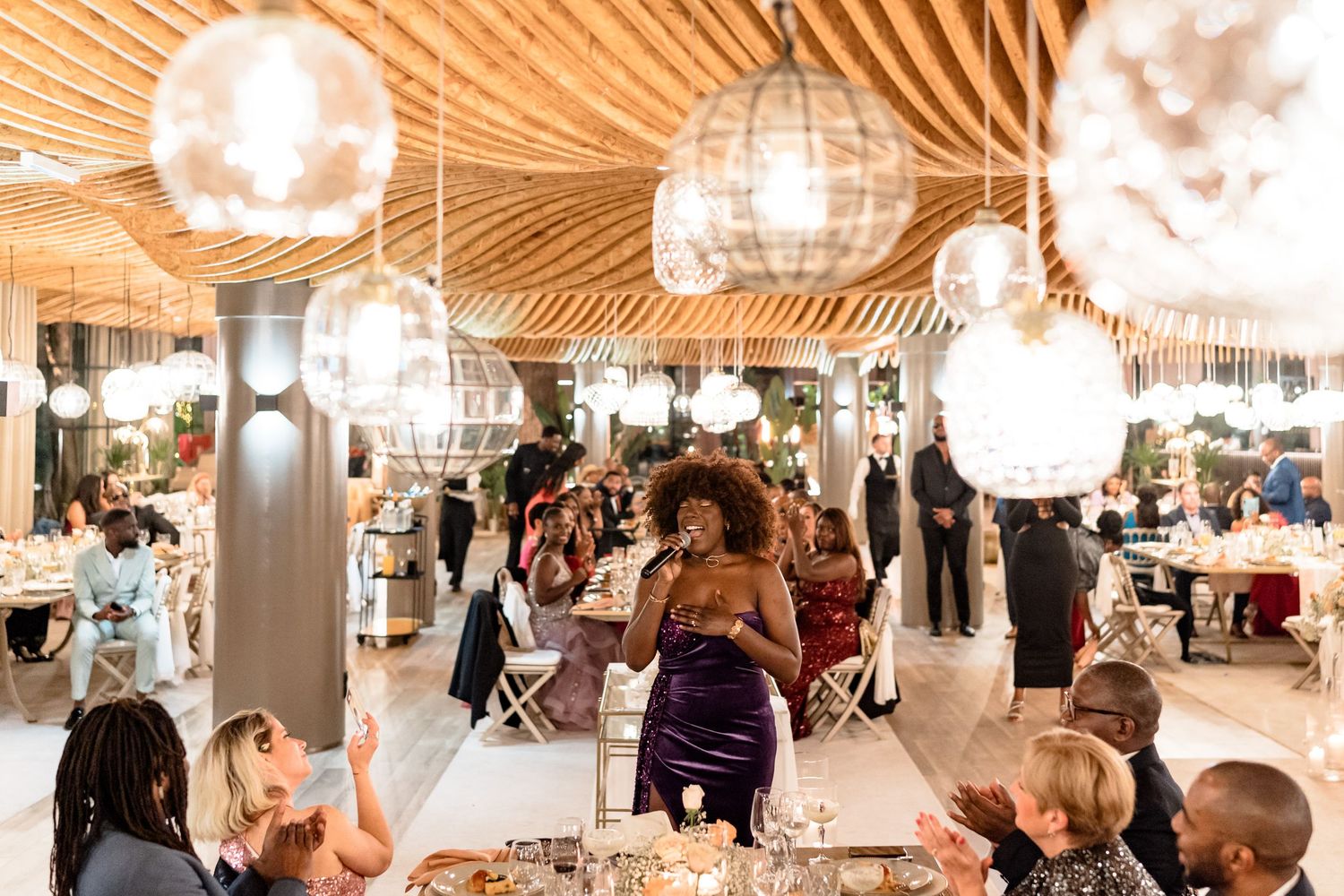 Wedding reception venue with glowing orb lights and wooden ceiling details.