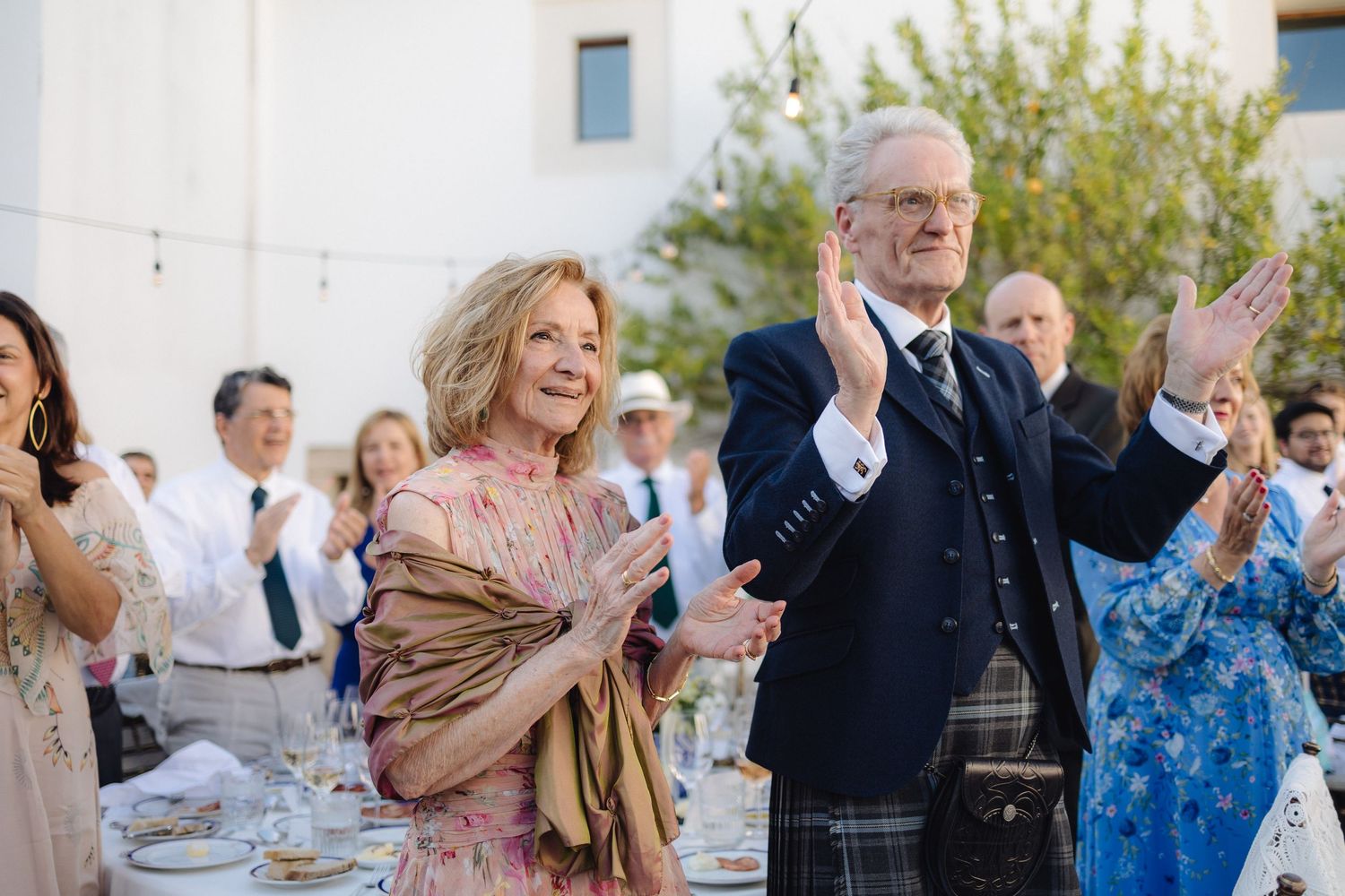 Wedding guests dancing and celebrating at an outdoor reception.