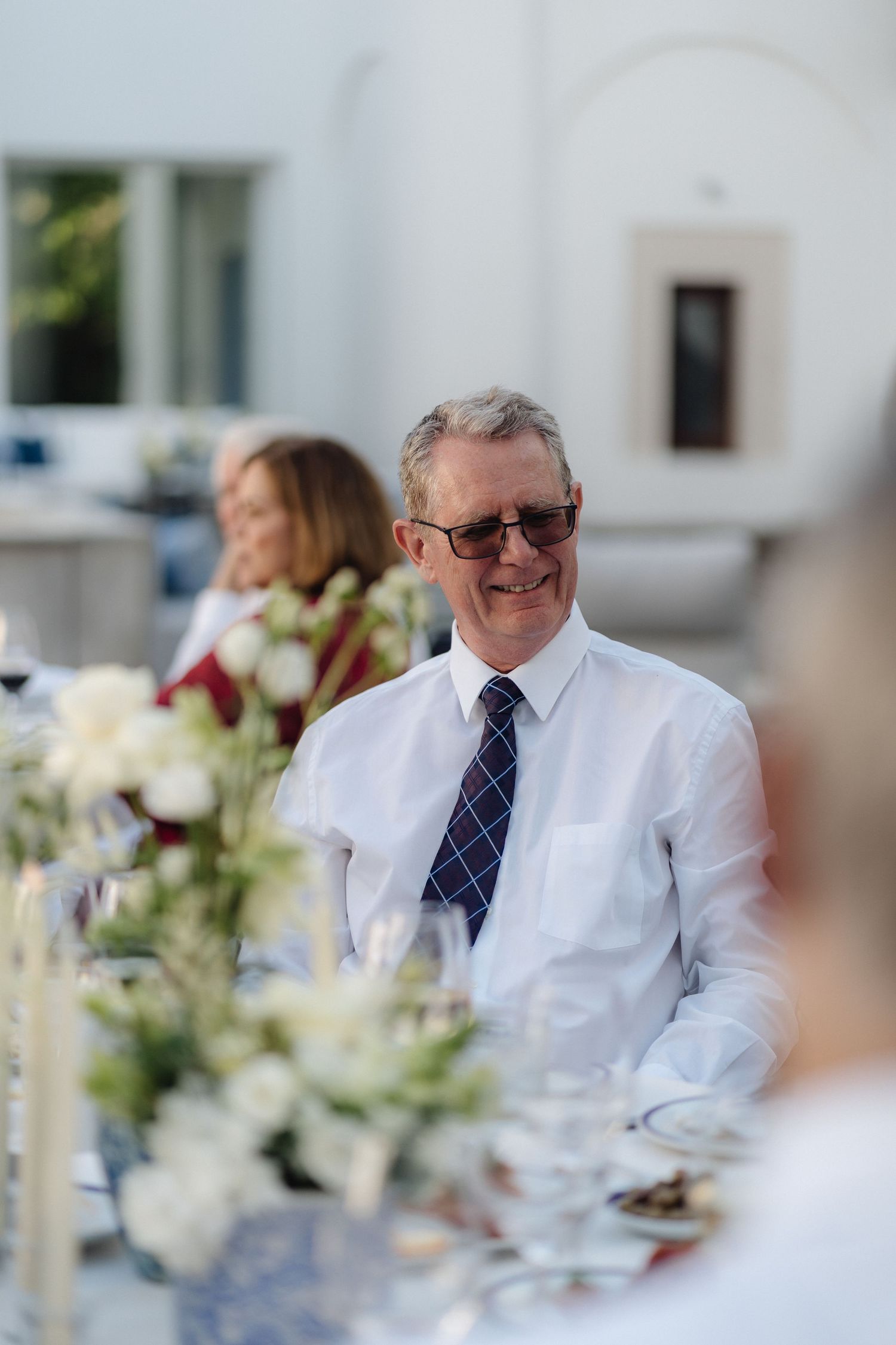Guests in formal attire enjoying conversation at an outdoor dinner party.