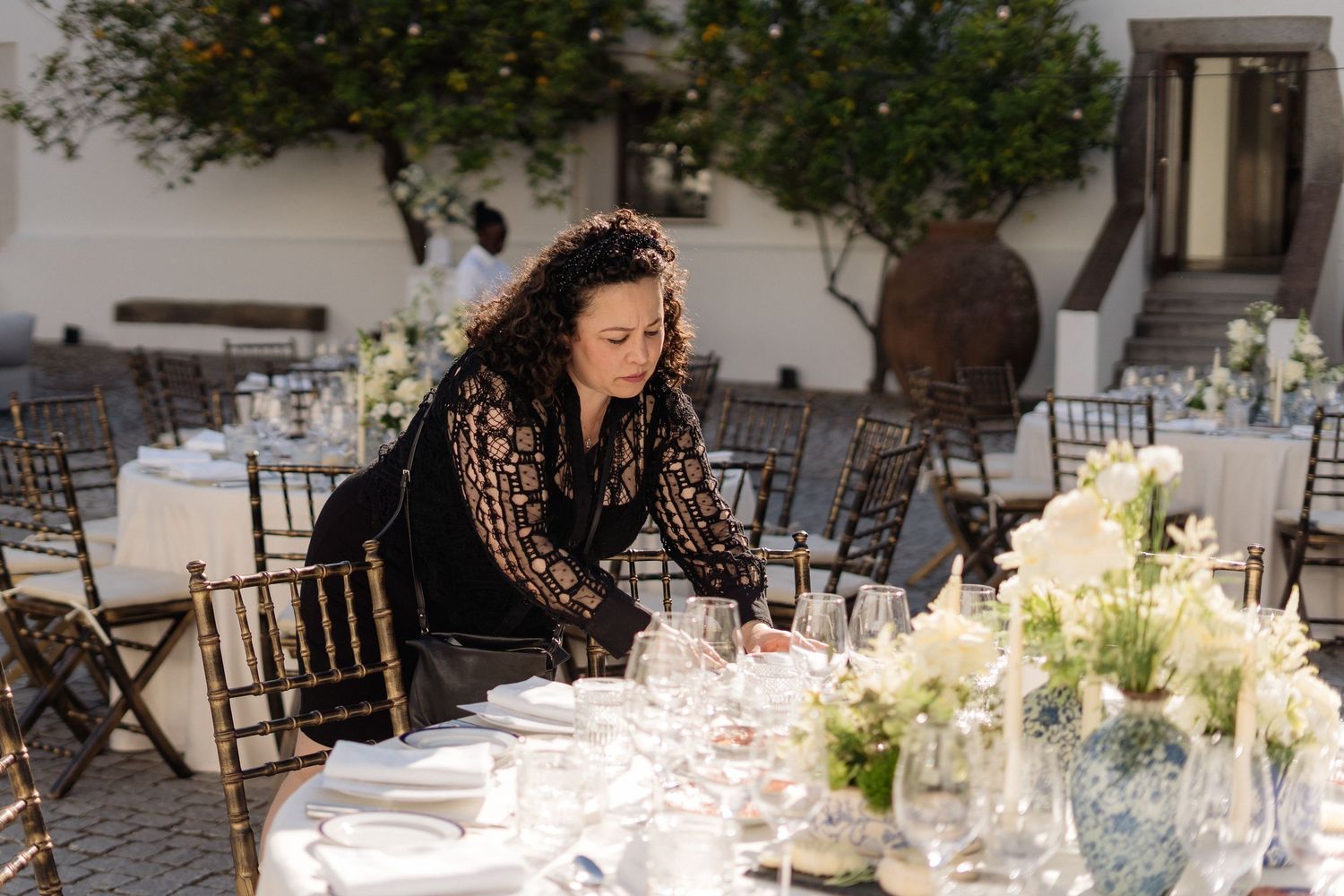 Elegant outdoor wedding reception setup with white tablecloths and floral centerpieces in a Mediterranean courtyard.
