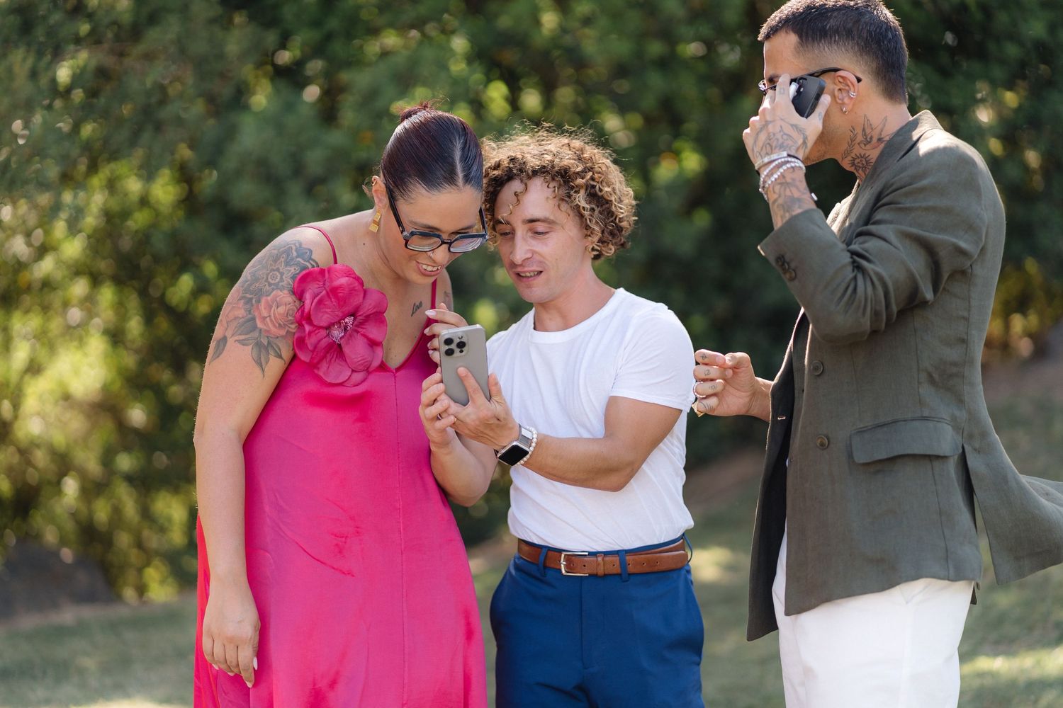 Small group interacting at outdoor wedding event in summer garden setting.