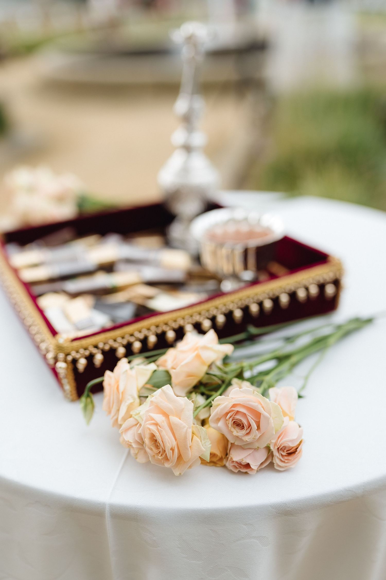 Peach roses beside an ornate box with decorative trim on white tablecloth.