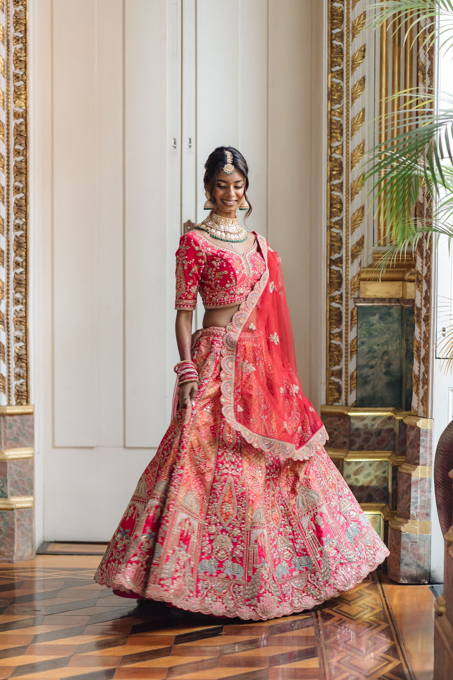 Ornate room with gilded mirrors showcasing a red embroidered lehenga.