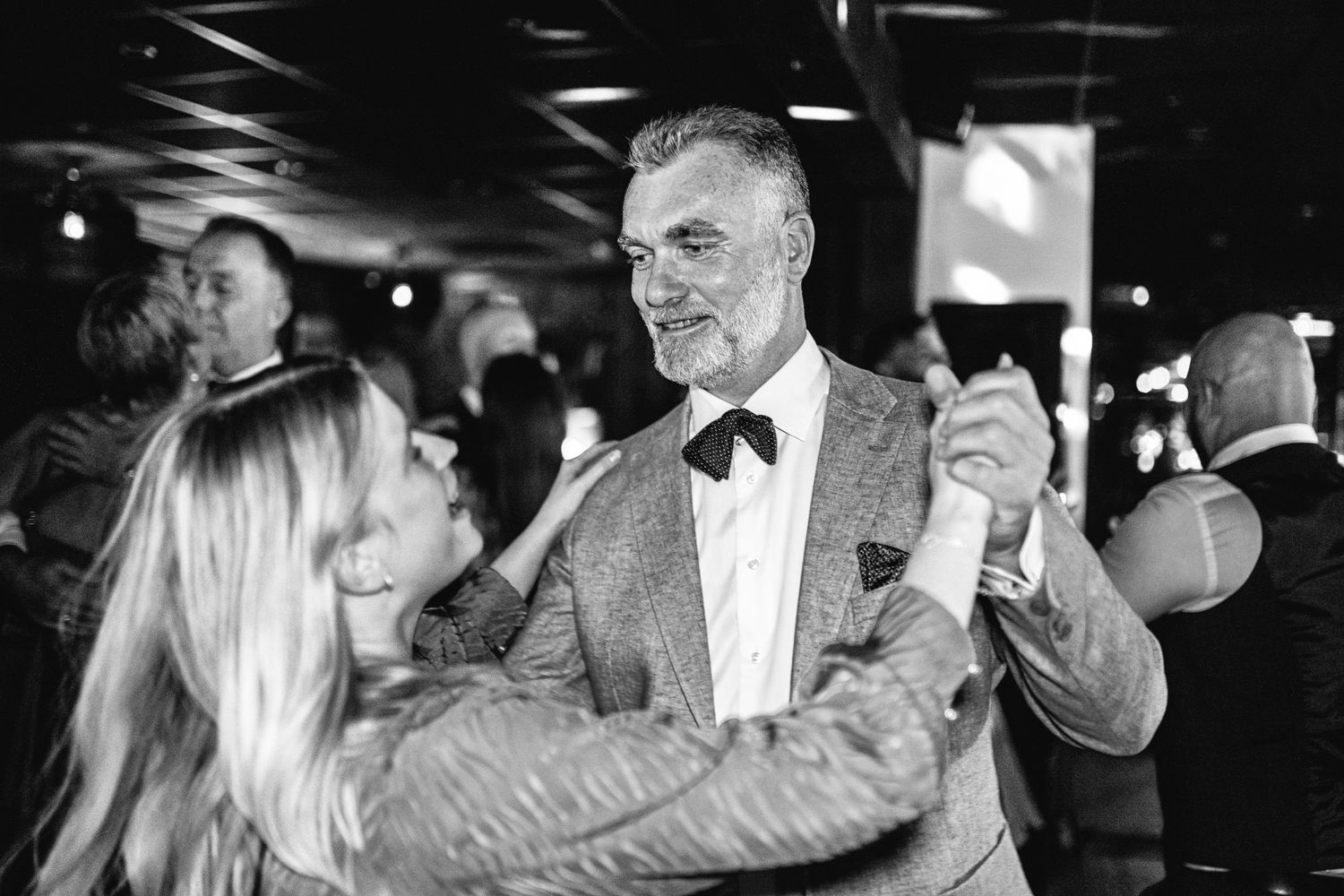 Couples dancing together at an elegant evening wedding reception with dramatic lighting.