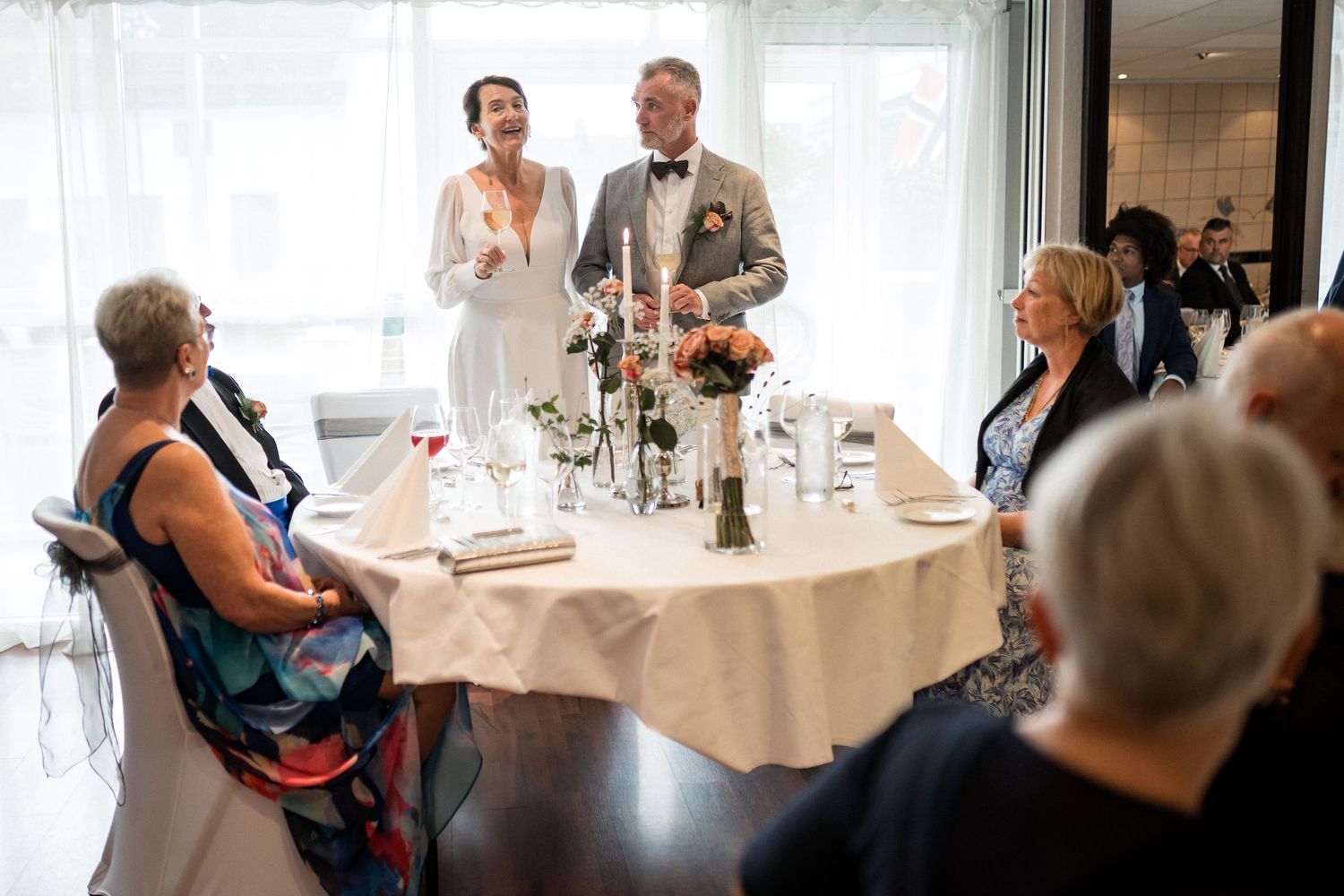 Wedding reception dining room with natural light streaming through large windows.