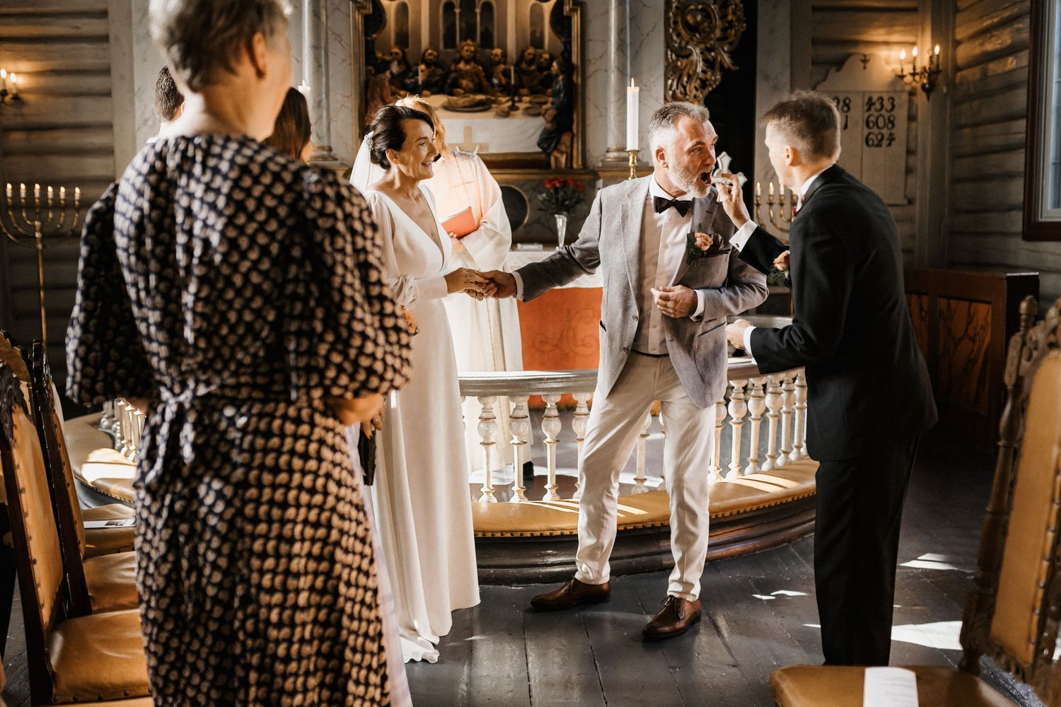 Wedding celebration in a grand hall with guests socializing and dancing.
