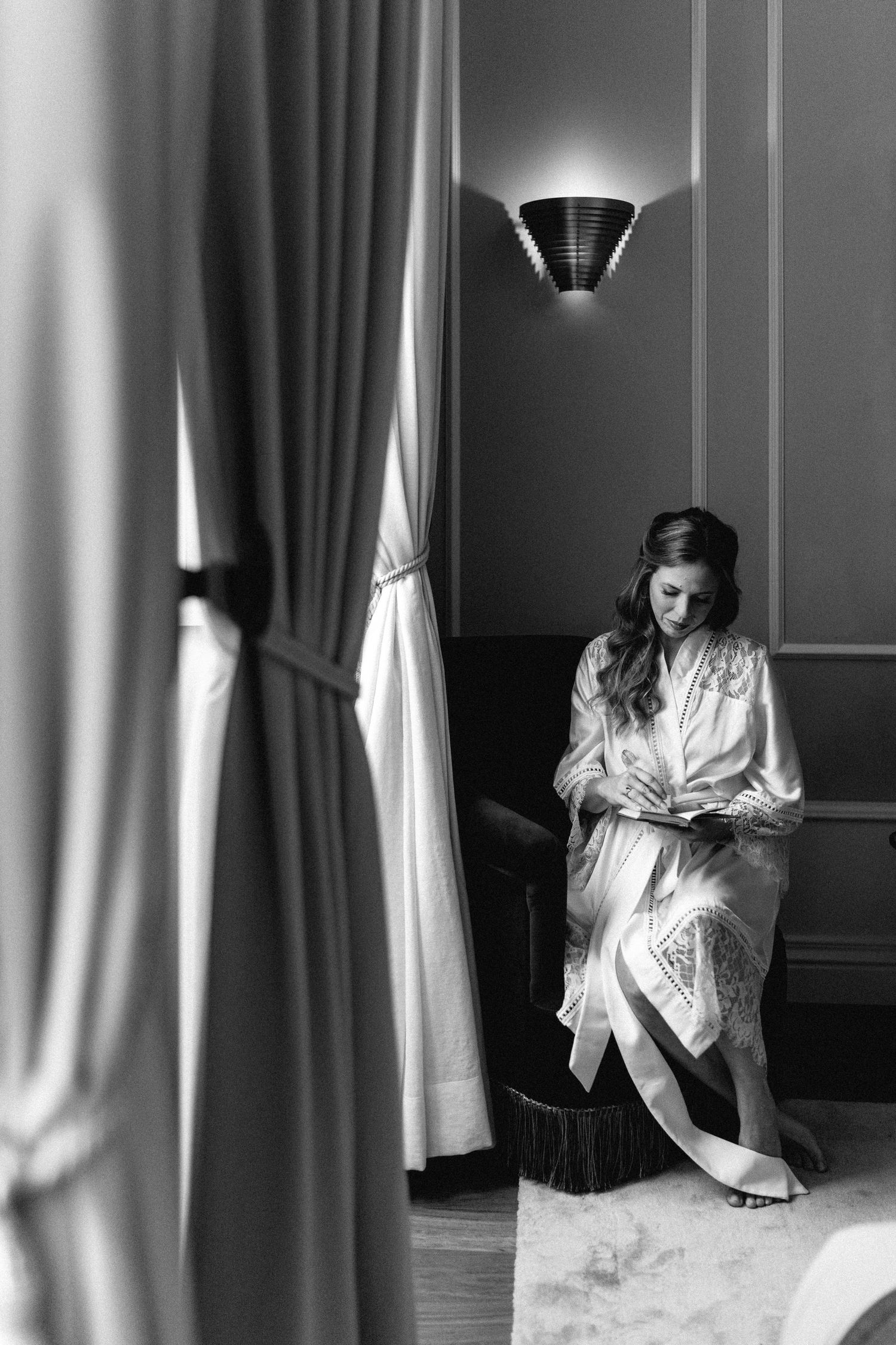 Dramatic black and white photos showing a figure in white against curtained windows.