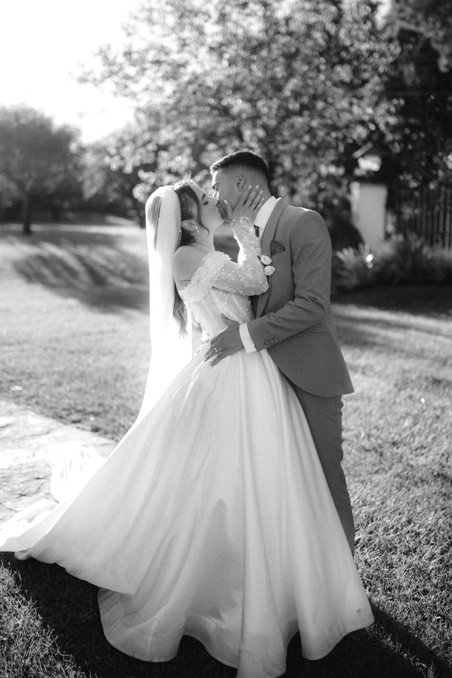 Romantic black and white wedding couple photos in a garden setting with flowing dress details.