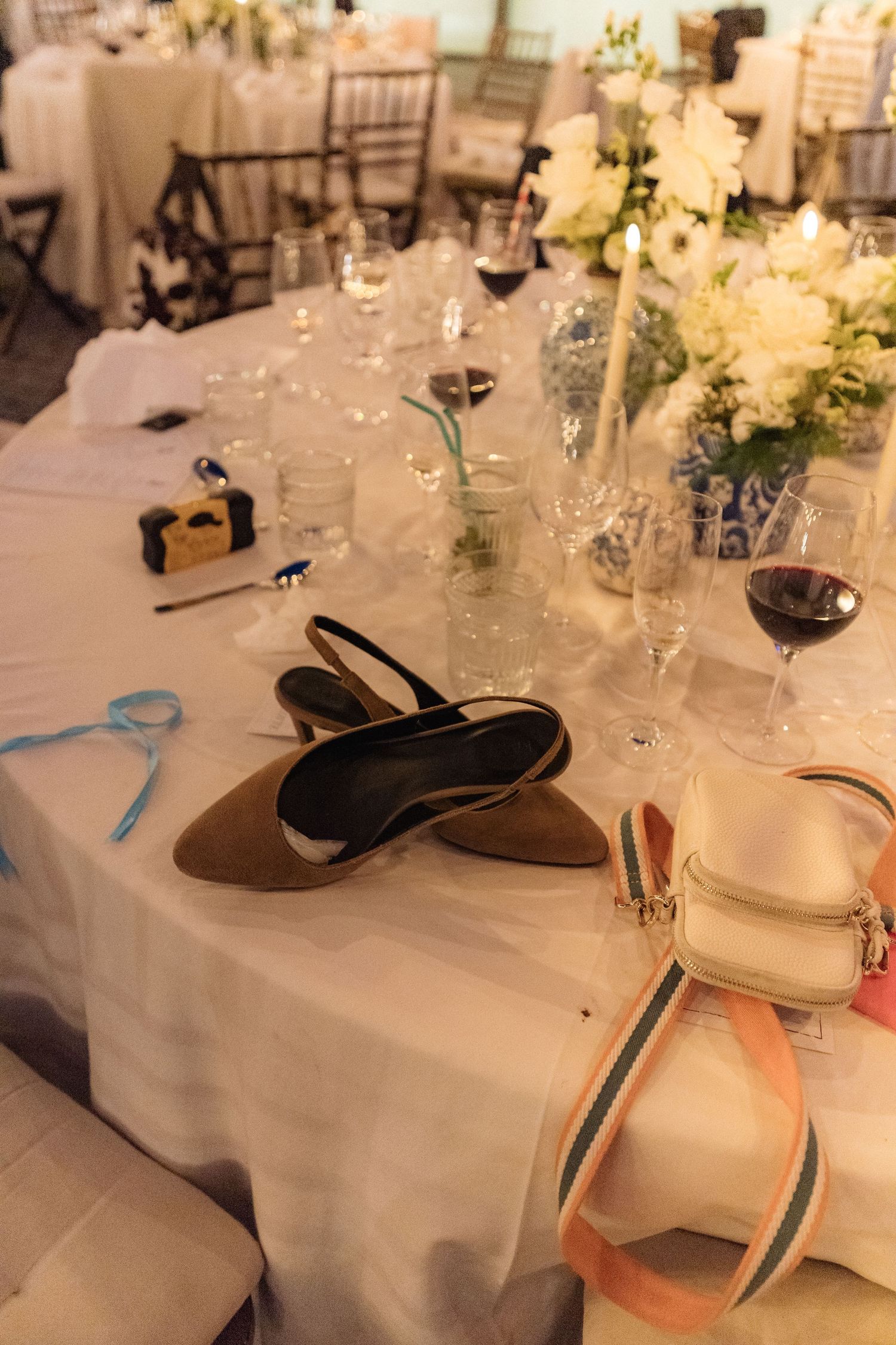 Elegant wedding reception table setting with white linens and floral centerpieces.