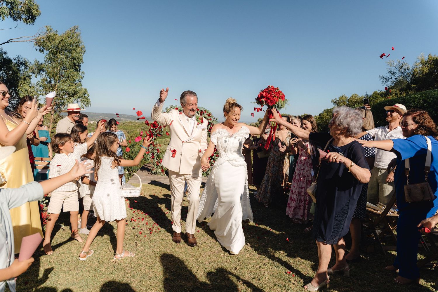 Wedding celebration with guests gathered outdoors under blue skies.
