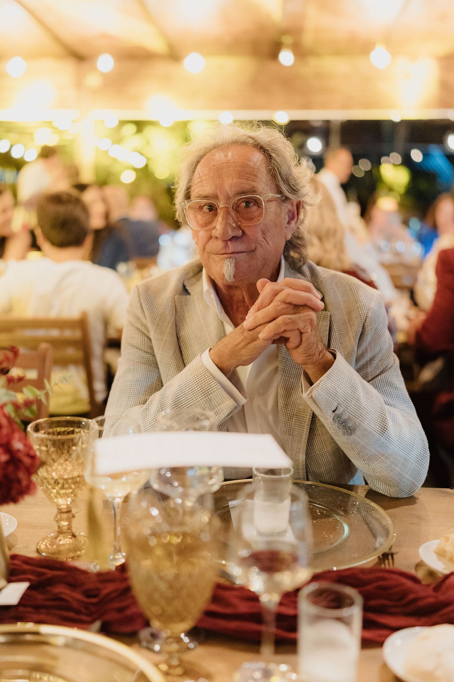 Formal dinner guests seated at tables with crystal glasses and burgundy table settings.