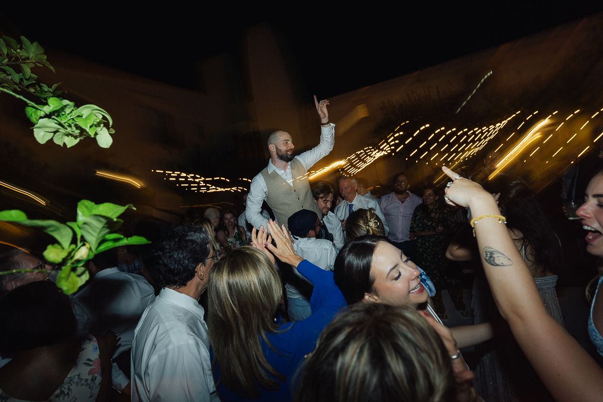 Dark reception venue with string lights and dancing wedding guests.