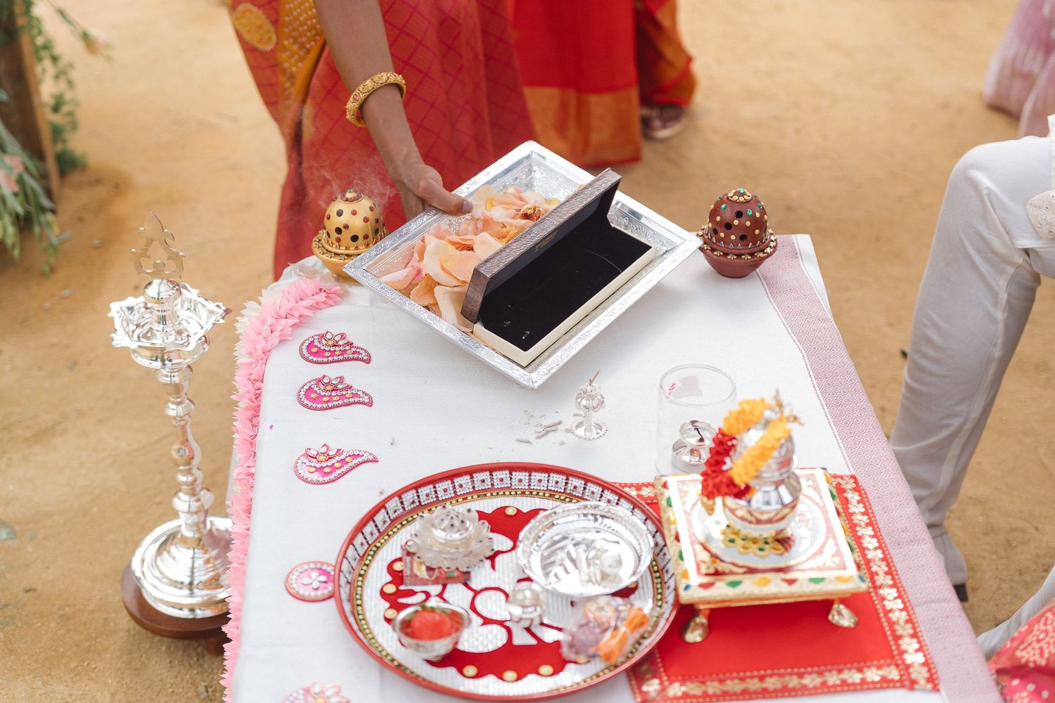 Traditional Indian wedding ceremony items and decorations arranged on pink and white table settings.