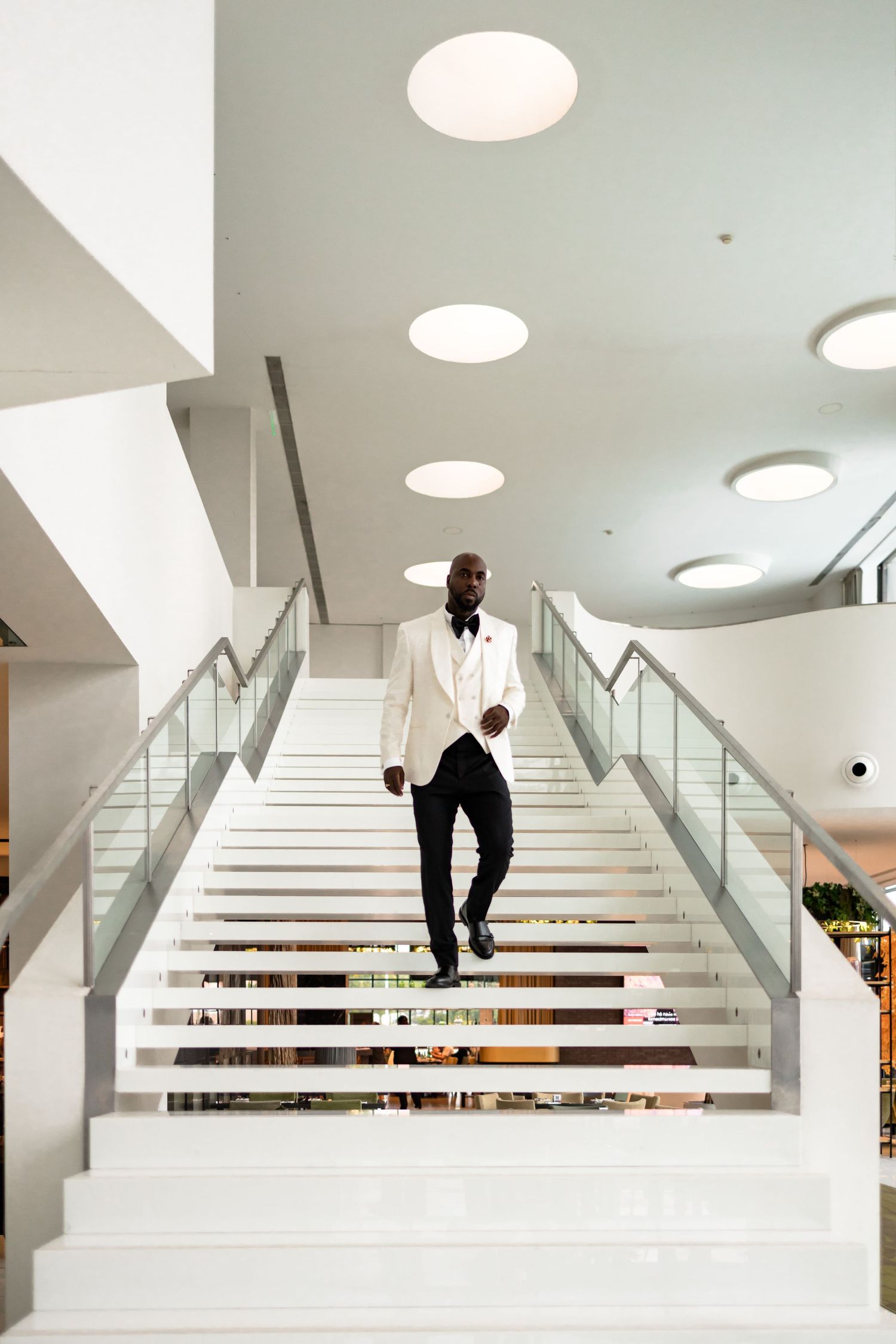 A series of photos showing a person descending modern white stairs in a bright interior space.