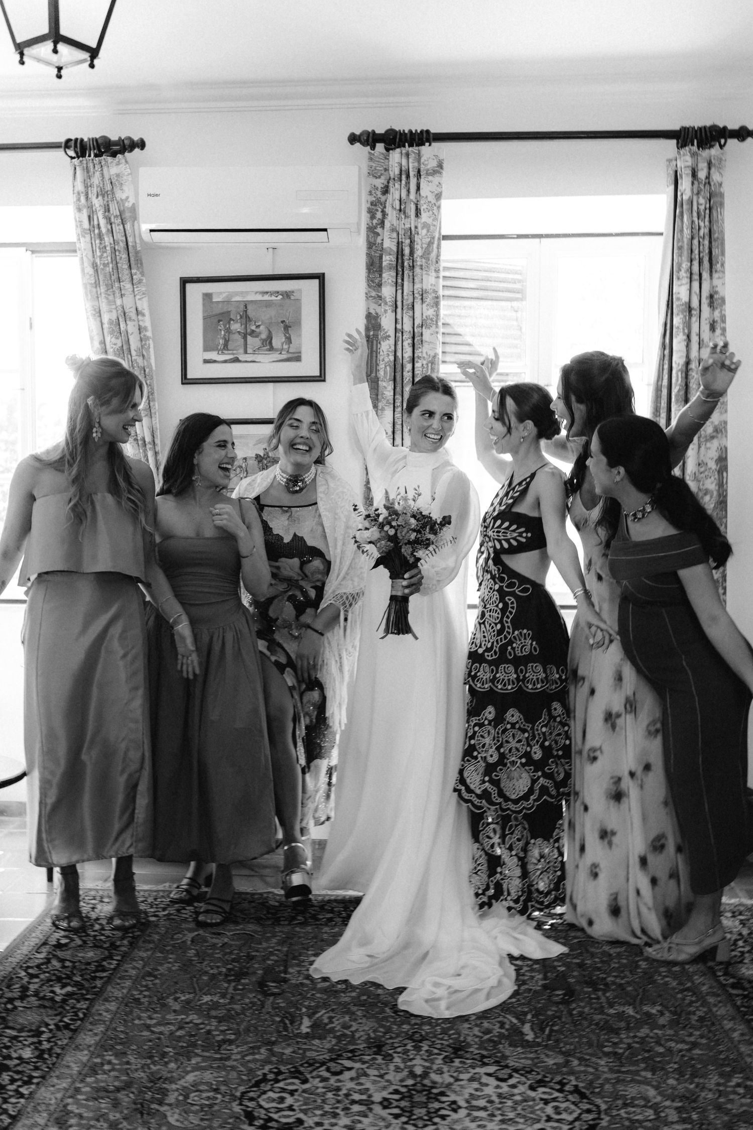 Wedding celebration with group dancing in elegant indoor setting with floral curtains.