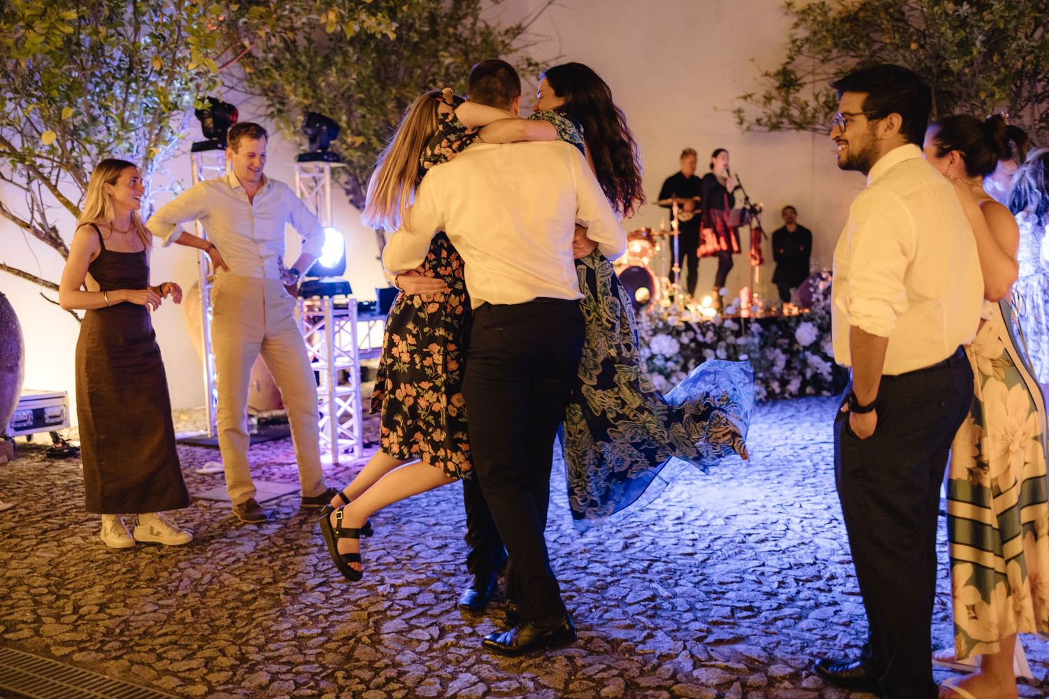 Guests dancing at night under ambient lighting at outdoor wedding venue.