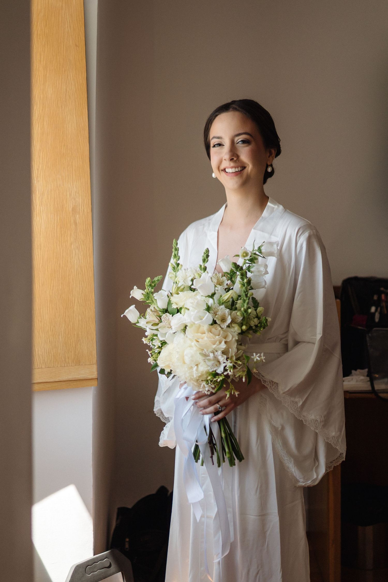 Wedding preparation photos showing white bridal bouquet and robe in natural light.
