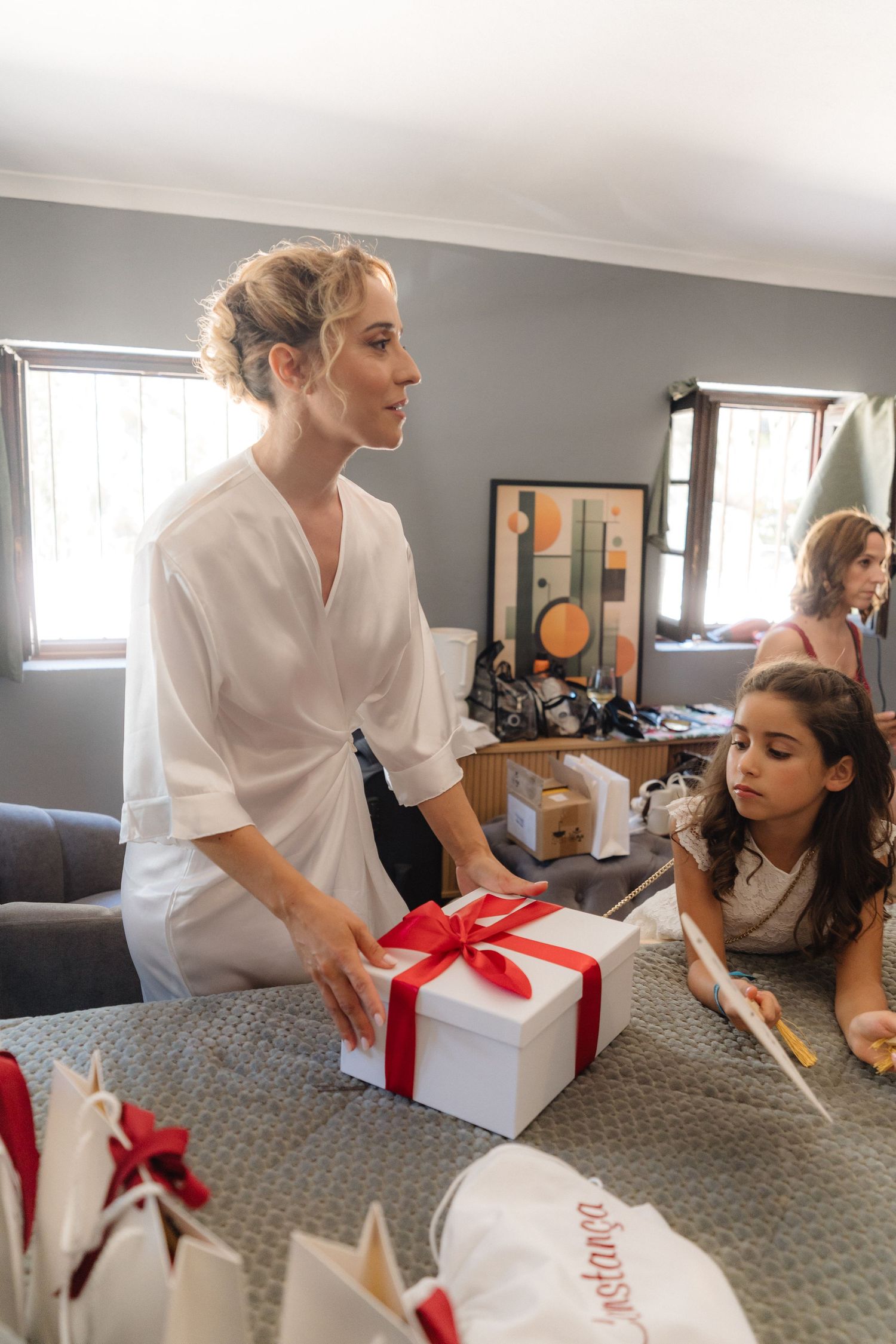White gift boxes with red bows being presented during wedding preparations.