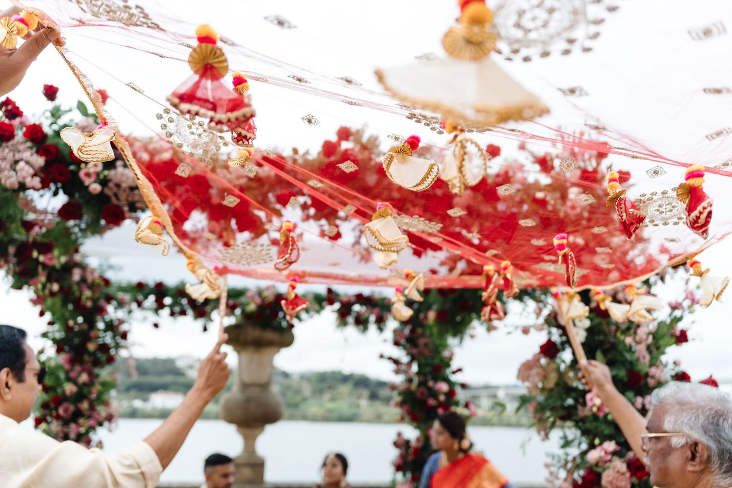Outdoor wedding ceremony setup with floral decorations and flowing red fabric canopy.