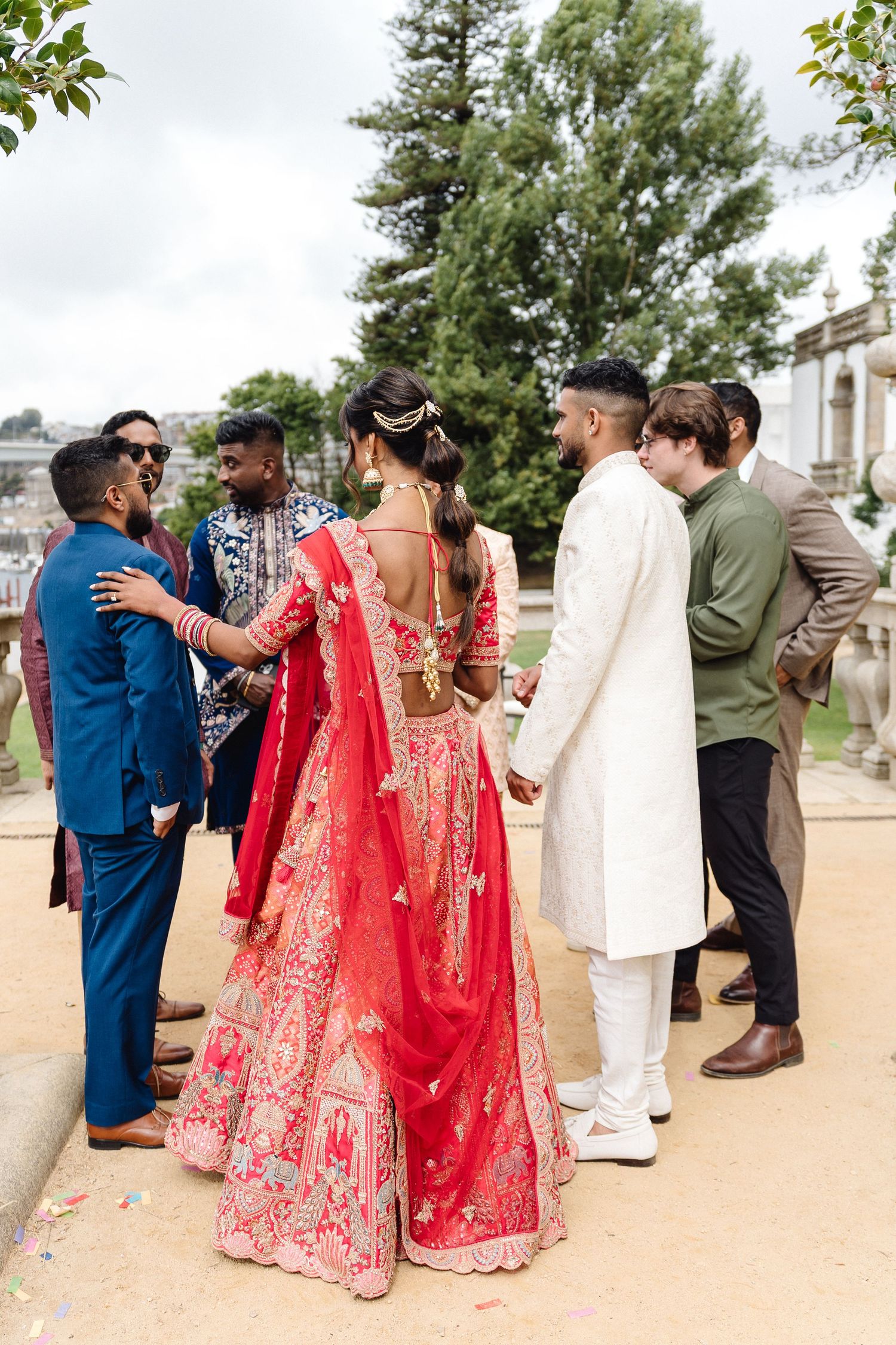 Wedding guests in traditional attire gather outdoors for conversation during celebration.