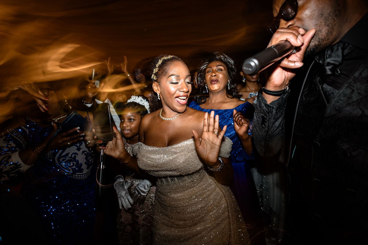People dancing and celebrating at a lively party with warm lighting and energetic atmosphere.