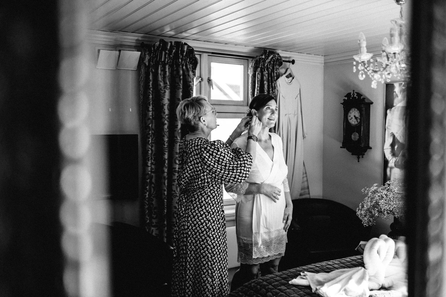 A romantic bedroom interior with chandelier and natural light streaming through windows.