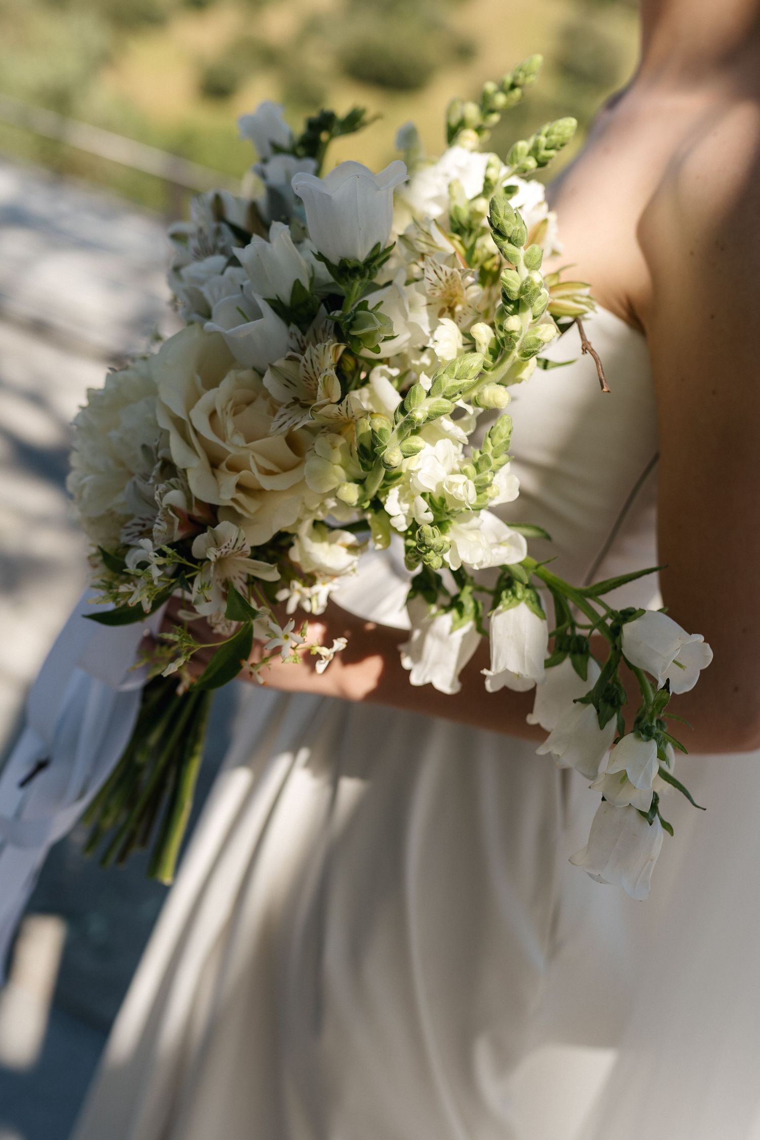 Elegant white and green bridal bouquet with delicate flowers in natural light.