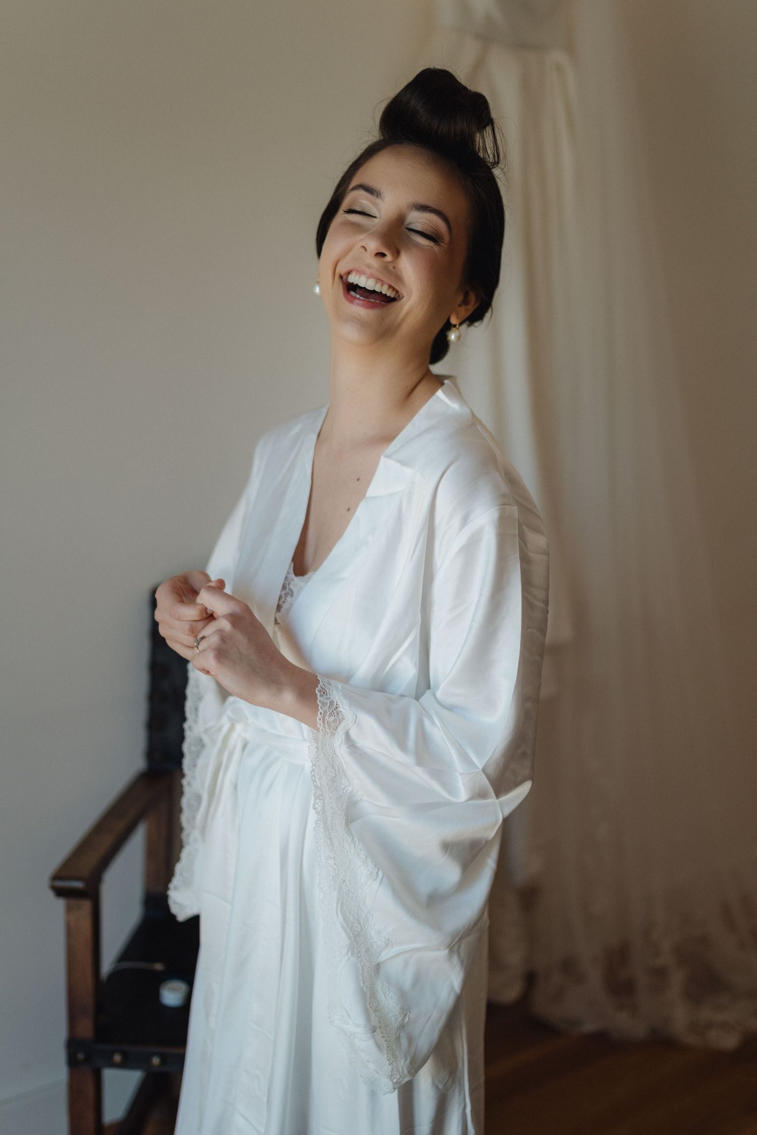 Candid sequence of a person in a white robe laughing joyfully during wedding preparations.