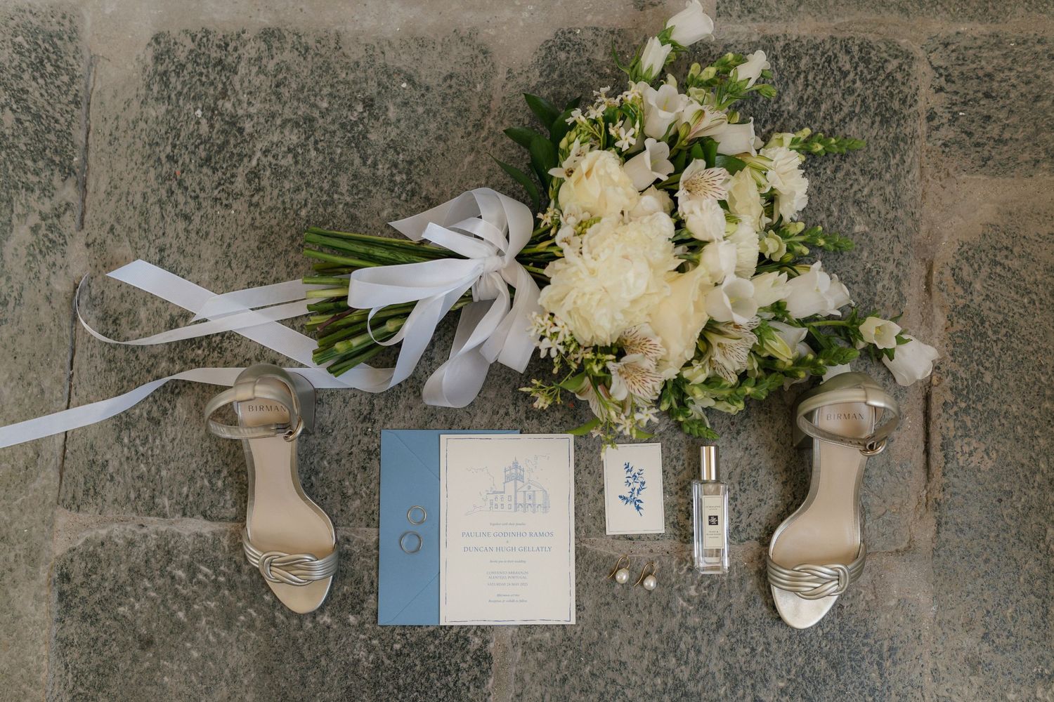 Wedding accessories and floral arrangements displayed on textured stone surface.