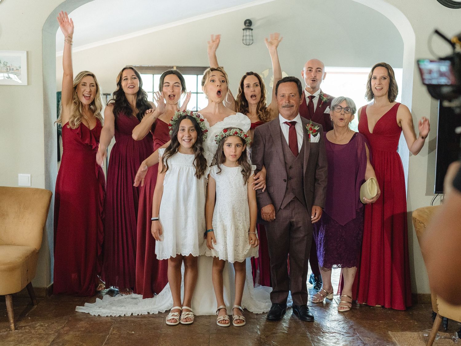 Large group photo of wedding party members wearing coordinated burgundy and white attire.