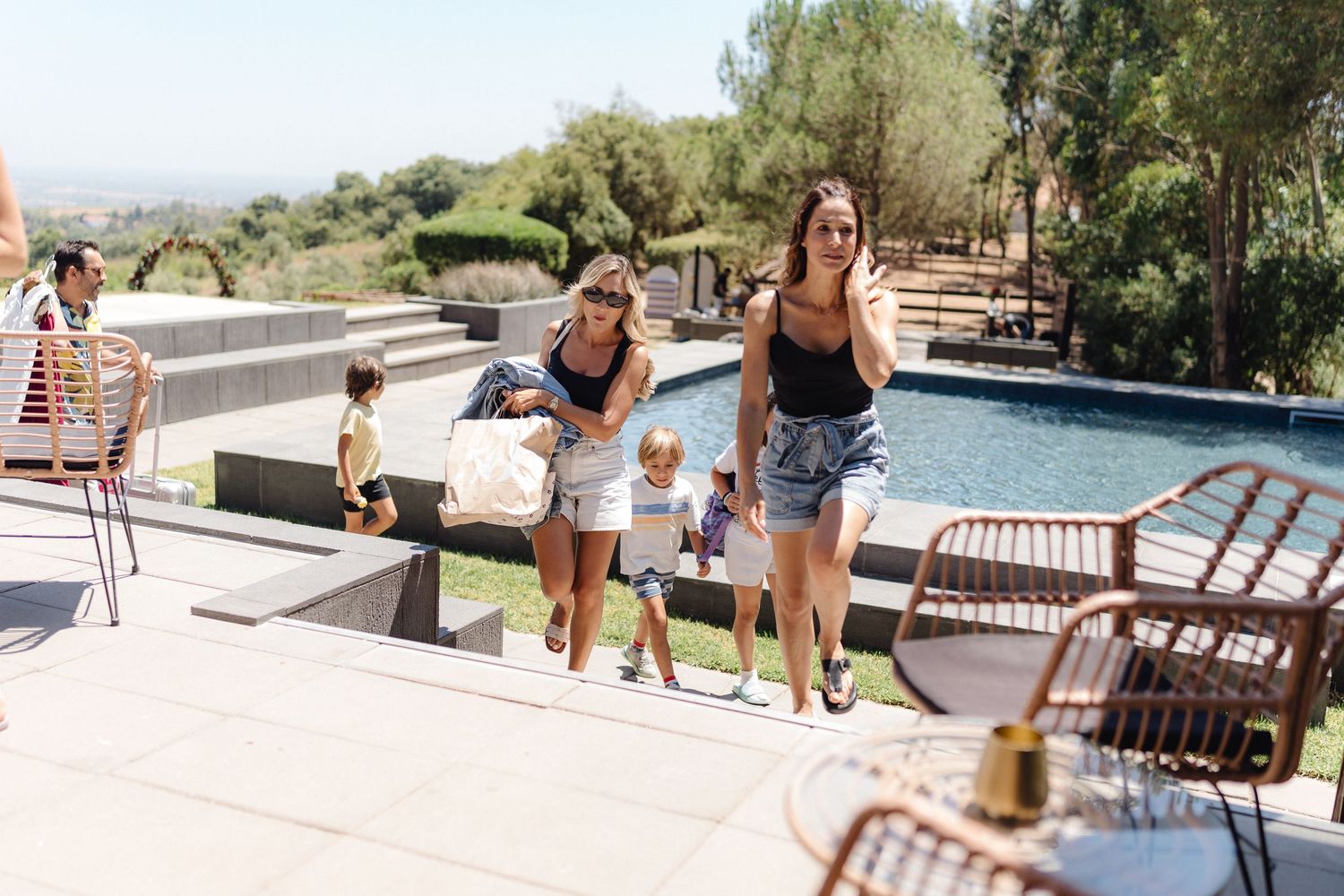 Friends enjoying a sunny day by a luxurious poolside with outdoor furniture and mountain views.