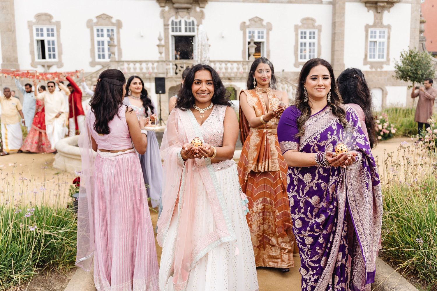 Wedding party members in coordinated pink and purple outfits posing together outdoors.