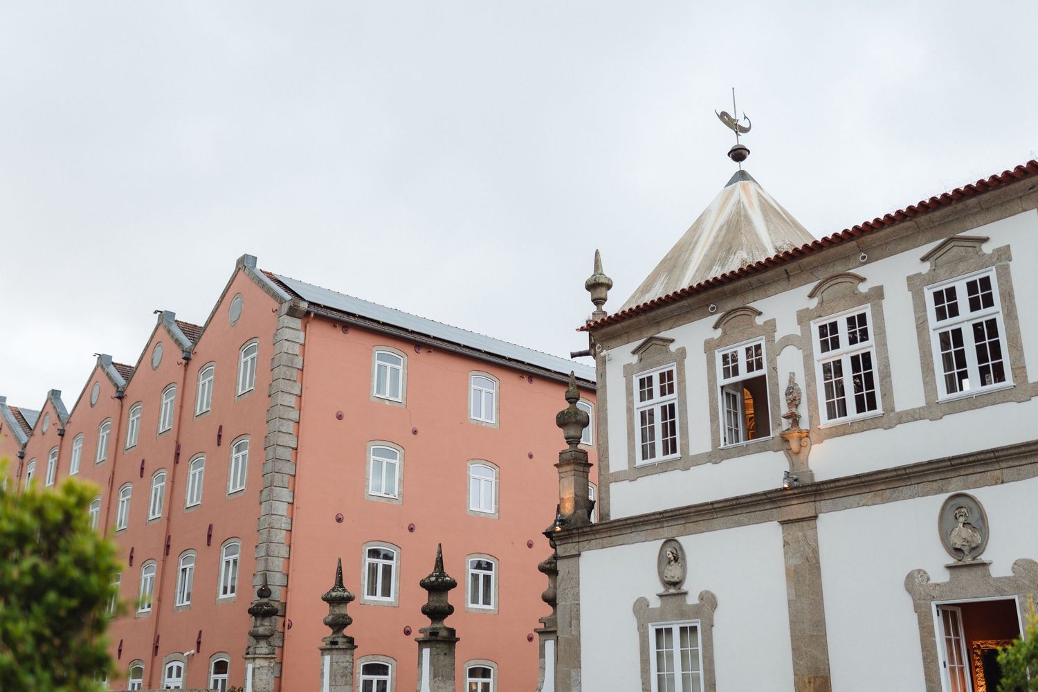 Historic pink and red brick buildings with white trim line a cobblestone street in a European town center.