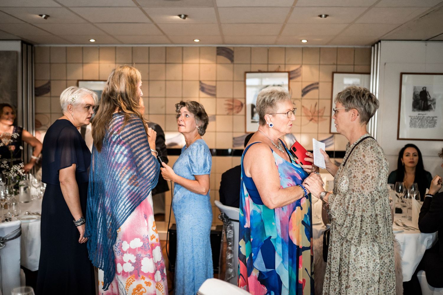 Wedding guests in colorful dresses mingle during reception.