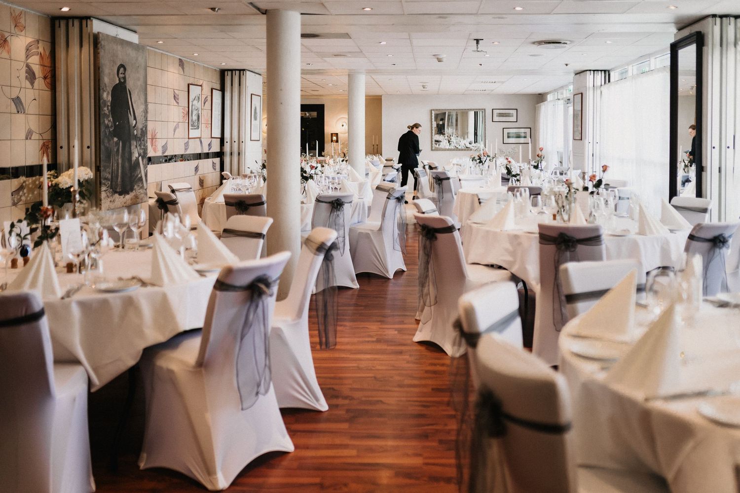 Banquet hall set up with white-covered tables and chairs in neat rows.